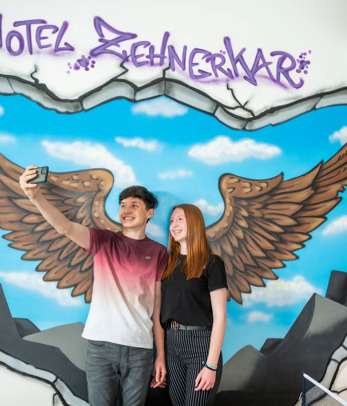 Jugendliche machen Fotos vor cooler Photowall im Jugendraum